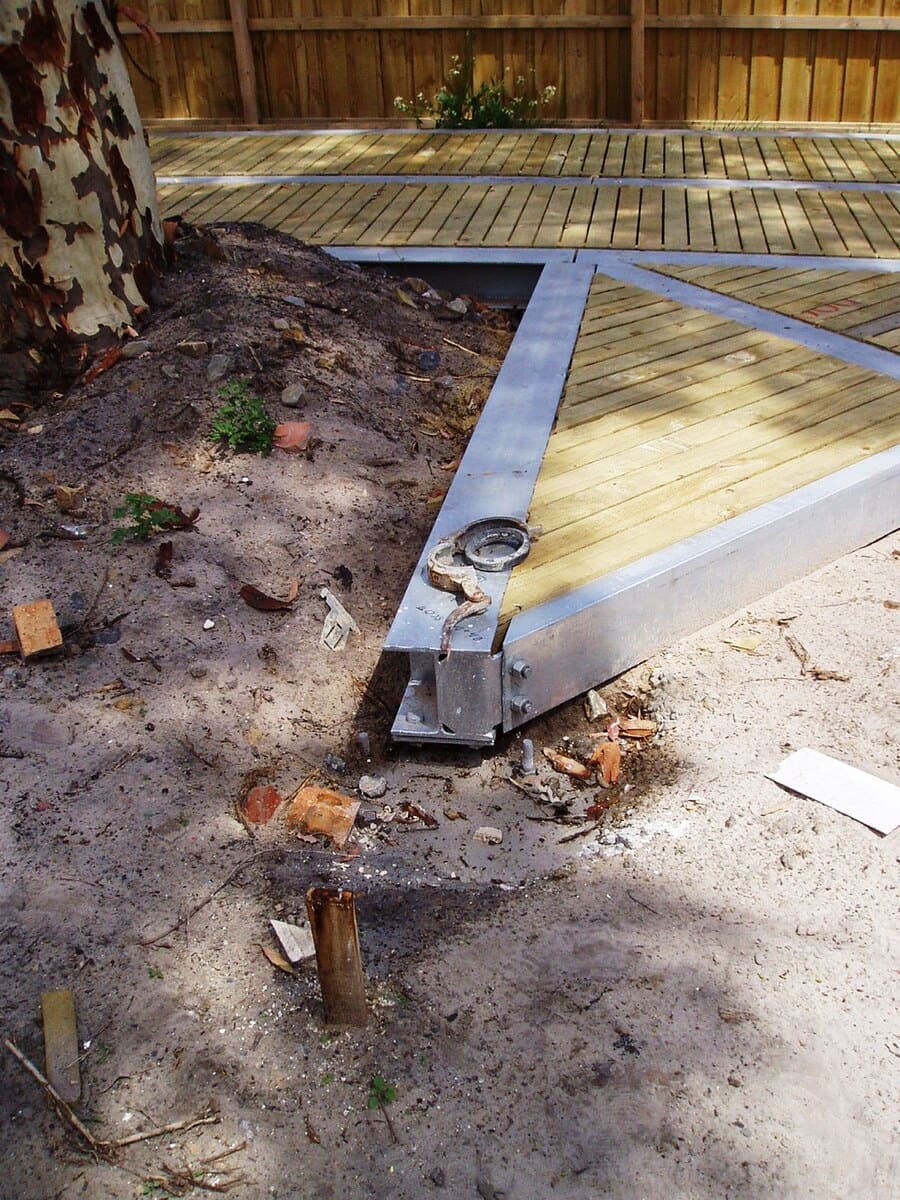 A galvanised steel edge beam on a pier footing beside the trunk of the Spotted Gum during construction in November 2005, with the timber deck behind.